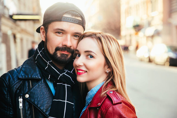 Outdoor fashion portrait of stylish couple kissing on sunset at the city street, wearing biker leather total black rock n roll look - Zdjęcie, obraz