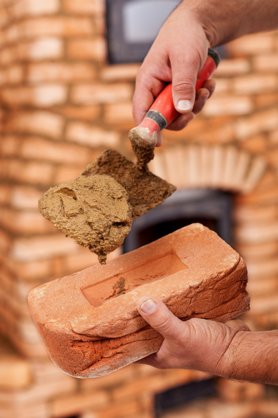 Строительство каменного обогревателя - крупный план на рабочих руках
 - Фото, изображение