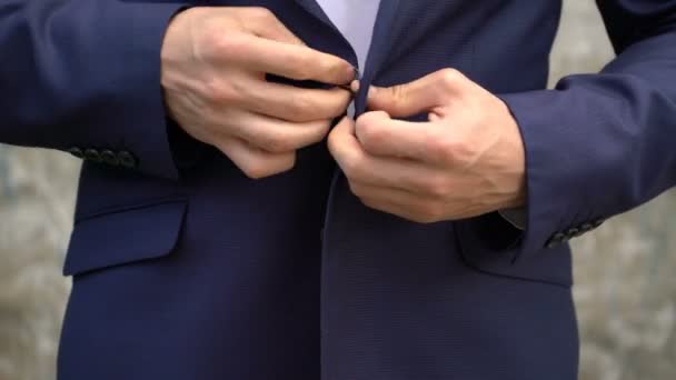 De man vastmaakt buttons op zijn jasje close-up. - Video
