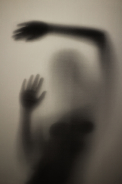 Τρομακτικό σιλουέτα ενός κοριτσιού πίσω από ένα ποτήρι στο μπάνιο στο φως - Φωτογραφία, εικόνα