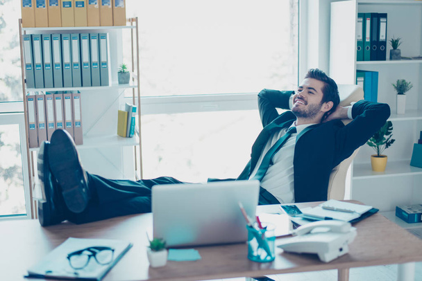 Lieto giovane uomo d'affari sta riposando nel suo ufficio con i piedi su
  - Foto, immagini