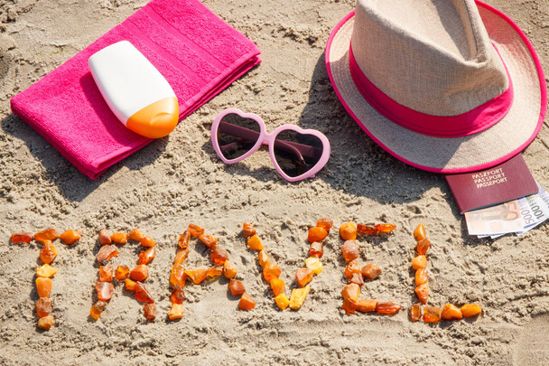 Inscription travel, accessories for sunbathing and passport with currencies euro on sand at beach, summer time concept - Photo, image