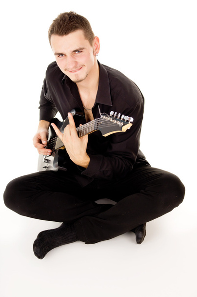Beautiful guy is playing the electric guitar, sitting on the flo - Фото, зображення