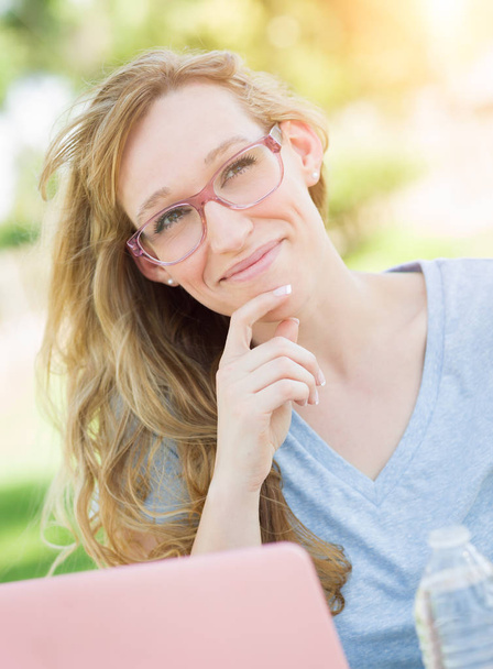 junge erwachsene Frau trägt Brille im Freien mit ihrem Laptop. - Foto, Bild