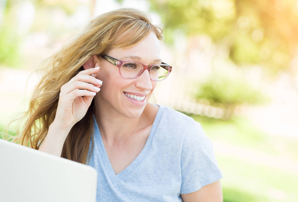 Jovem mulher adulta vestindo óculos ao ar livre usando seu laptop
. - Foto, Imagem