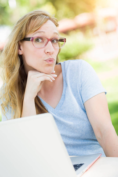Jovem mulher adulta vestindo óculos ao ar livre usando seu laptop
. - Foto, Imagem