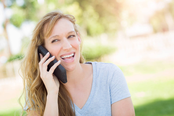 Jovem mulher adulta ao ar livre conversando em seu telefone inteligente
. - Foto, Imagem