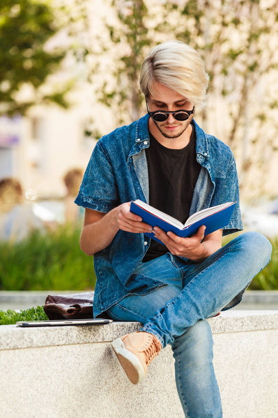 Hipster guy holding notebook sitting on ledge - Foto, Imagen