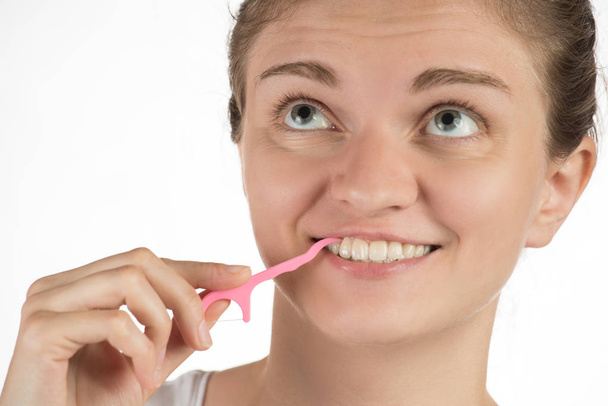 Гигиена полости рта. Молодая девушка чистит зубы нитью
,  - Фото, изображение