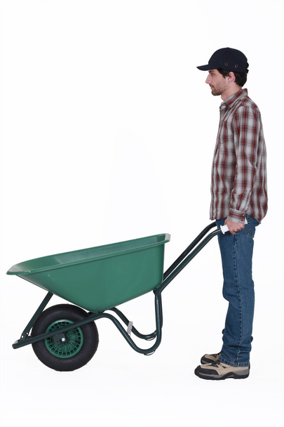 Profile shot of man stood with wheelbarrow - Zdjęcie, obraz