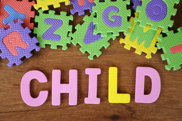 Dziecko wykonane z pianki kauczukowej i gumowych kolorowe puzzle alfabet losowo pojęciowy słowo zorganizować. Na białym tle na drewno tekstury tło.   - Zdjęcie, obraz