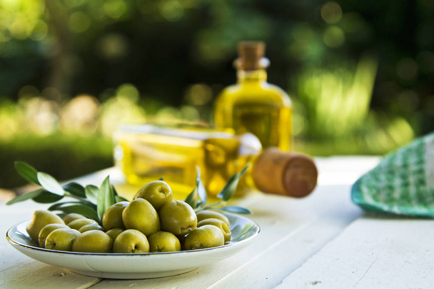 Talerz oliwek i butelki z oliwy z oliwek na stole - Zdjęcie, obraz