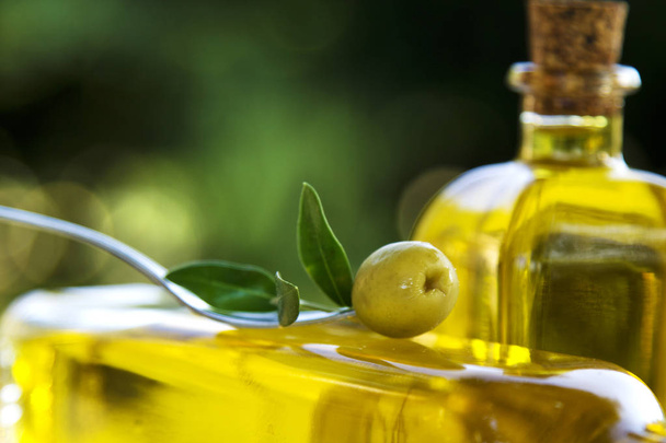 Widelec z oliwek na tle butelek oliwy z oliwek - Zdjęcie, obraz