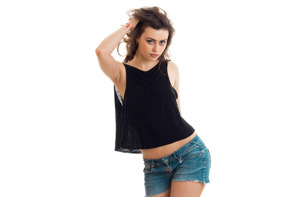 brunette teen in denim shorts and a black t-shirt sexy poses on camera - Foto, Imagem