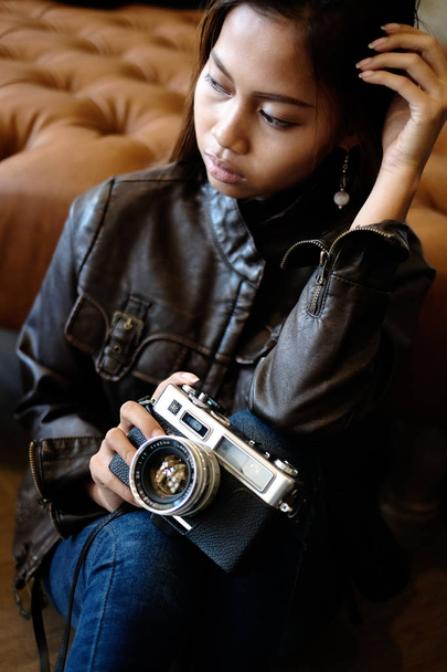 Gorgeous young woman in leather jacket, holding old retro film camera. Hipster,  Vintage Retro fashion style - Fotografie, Obrázek