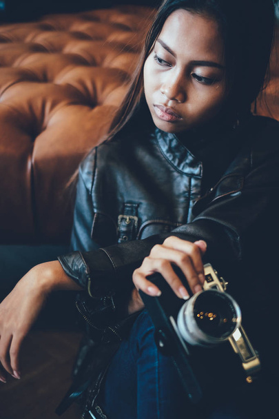 Gorgeous young woman in leather jacket, holding old retro film camera. Hipster,  Vintage Retro fashion style - Foto, imagen