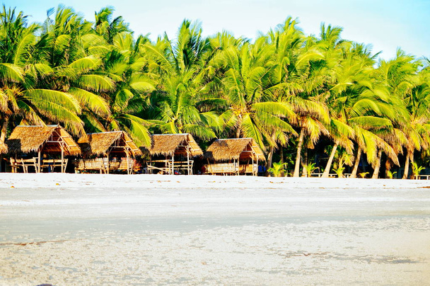 Mooie wit koraal zand strand met palmen en huisjes - Foto, afbeelding
