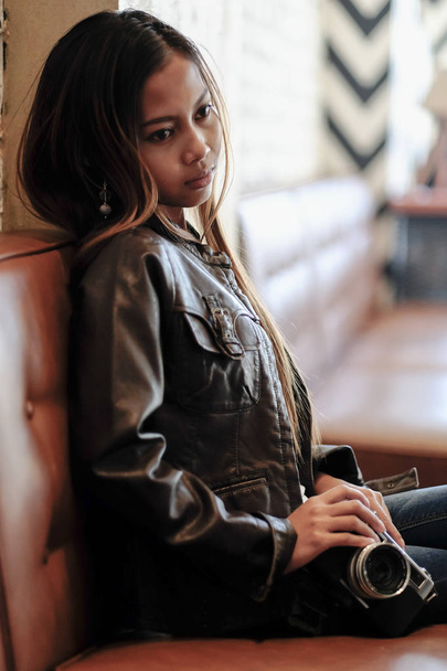 Gorgeous young woman in leather jacket, holding Vintage Retro film camera. Hipster,  Vintage Retro fashion style - Фото, зображення