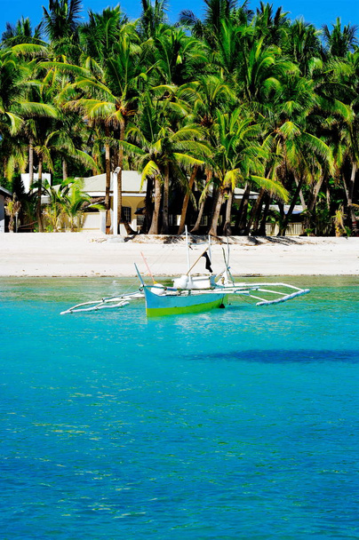 アジアの海の地平線上白い珊瑚砂のビーチの近くのターコイズ ブルー色の海海岸で午後に空漁船にドッキング。 - 写真・画像