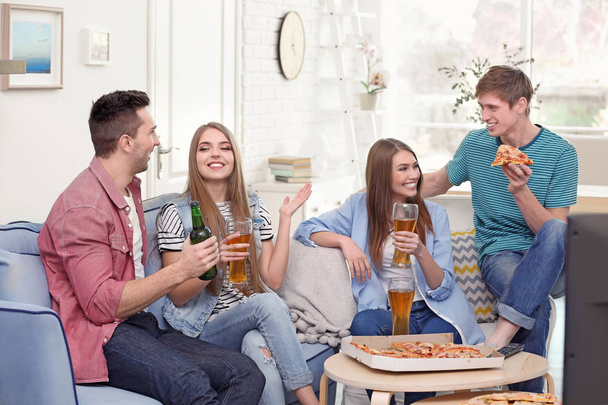 Freunde mit leckerer Pizza und Bier vor dem Fernseher zu Hause - Foto, Bild