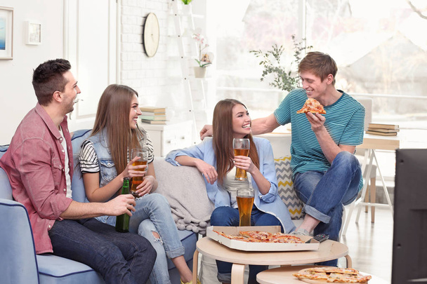 Friends with tasty pizza and beer watching TV at home - Photo, image