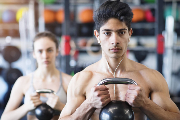 Young fit couple in gym exercising with kettlebell. - Fotoğraf, Görsel