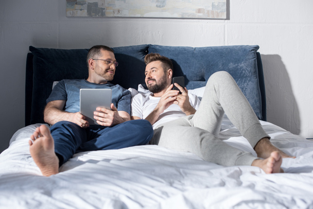 Гомосексуальная пара с помощью цифровых устройств
  - Фото, изображение
