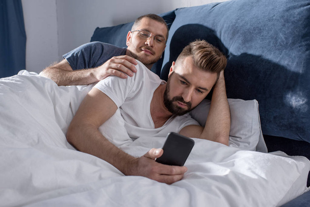 Homosexual couple using smartphone  - Φωτογραφία, εικόνα