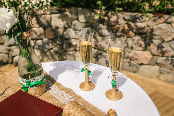 Two decorated glasses of champagne on the table in the yard at the wedding ceremony - Fotografie, Obrázek