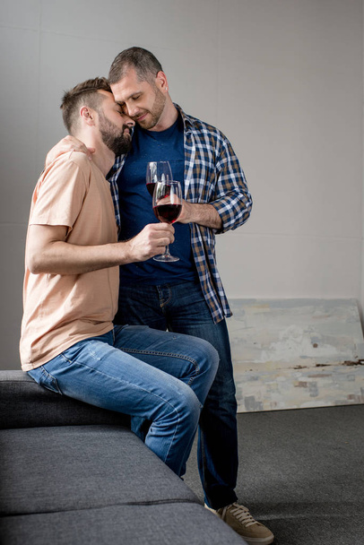 ομοφυλόφιλο ζευγάρι αγκαλιάζει και πίνοντας κρασί - Φωτογραφία, εικόνα
