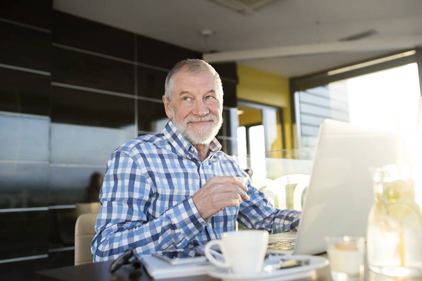 Senior businessman working on laptop in cafe - Фото, изображение