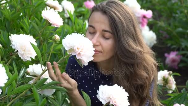 beautiful woman smelling a white peony flowers in the summer garden - Footage, Video