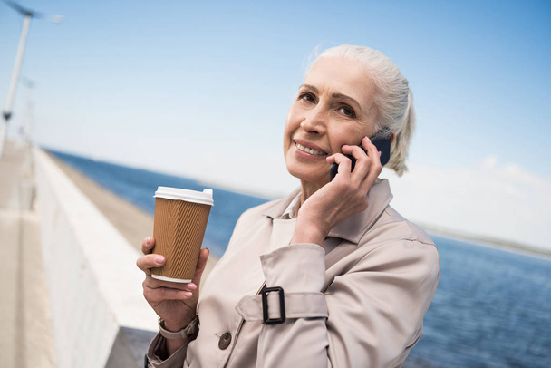 Ältere Frau telefoniert am Kai mit Smartphone - Foto, Bild