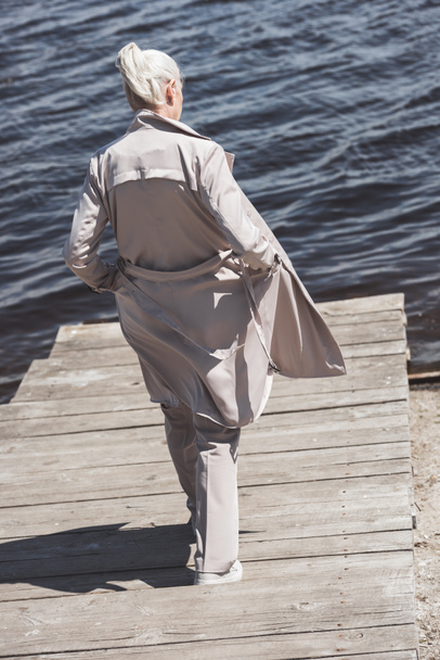elderly woman in coat walking at riverside - Photo, Image
