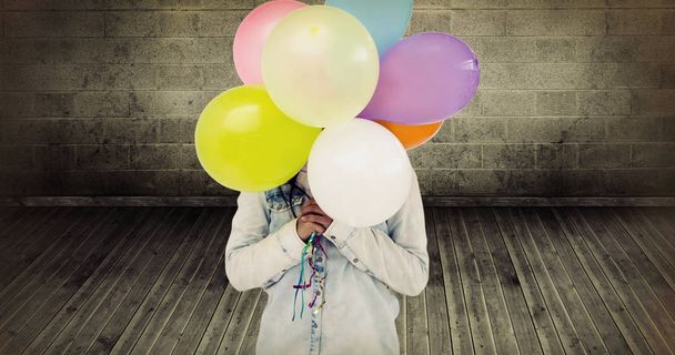 woman hiding her face with bunch of colorful balloons  - 写真・画像