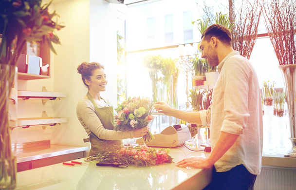 smiling florist woman and man at flower shop - 写真・画像