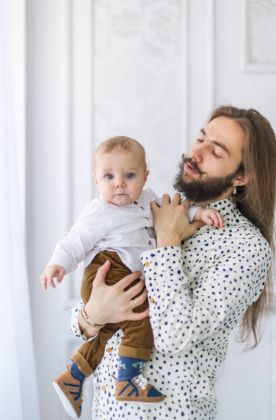 Jonge, bebaarde vader met baby op handen - Foto, afbeelding