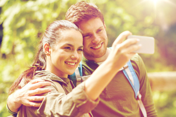 couple with backpacks taking selfie by smartphone - Valokuva, kuva