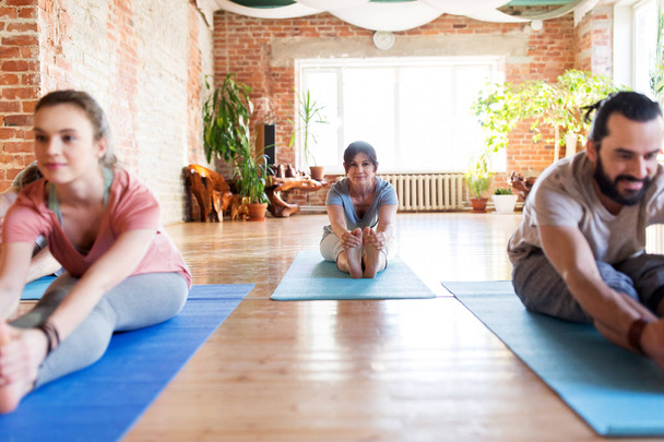 groupe de personnes faisant du yoga avant plier au studio - Photo, image
