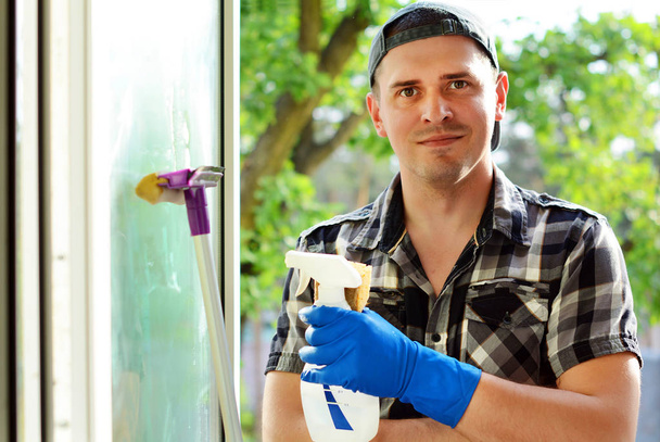 Jeune homme qui nettoie les fenêtres. Entreprise de nettoyage professionnelle
. - Photo, image