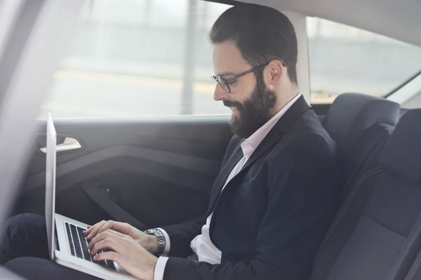 Biznesmen z laptopa w samochodzie - Zdjęcie, obraz