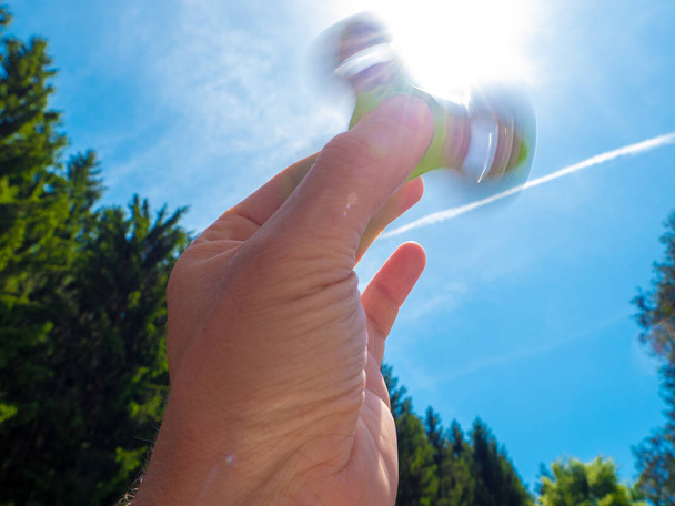 Mano masculina sosteniendo un fidget spinner
 - Foto, imagen