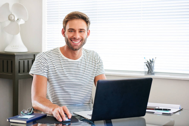 Tech savvy young man smiling at camera sitting behind computer - Zdjęcie, obraz