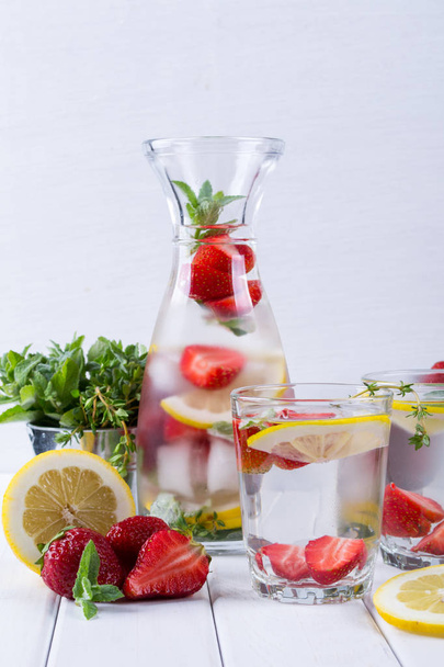 Mineral infused water with strawberry, ice, herb and mint leaves on white background, homemade detox soda water - Photo, Image