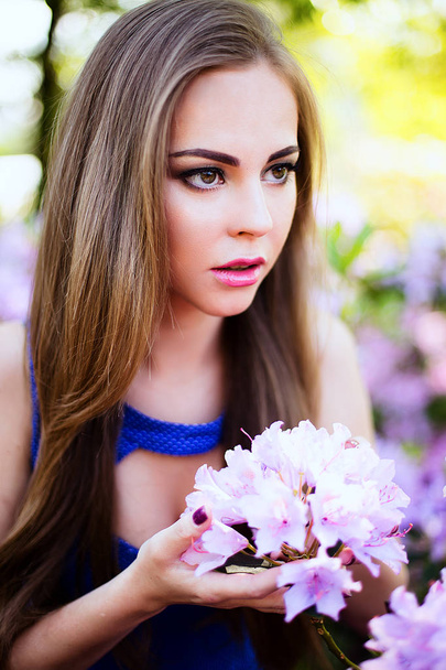 Portrét dívky v modrých šatech v zahradě s květinami - Fotografie, Obrázek