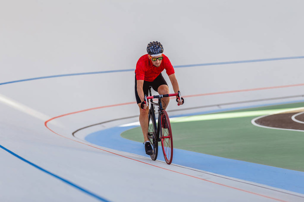 Young professional cyclist on a velodrome - Фото, изображение