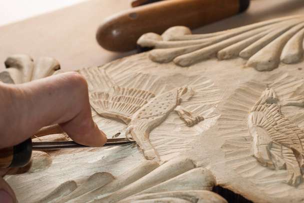 handen van een werkman snijden een bas-reliëf van hout, - Foto, afbeelding