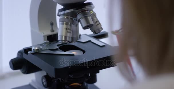 Ciddi klinisyen laboratuvar kimyasal element okuyor. Mikroskobik lens yakın çekim. Mikro analizde için hazırlanan mikroskop slayt örneğinde - Video, Çekim