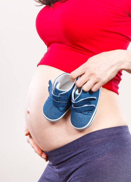 Pregnant woman with baby shoes, concept of expecting for baby - Фото, зображення