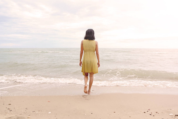Young woman walking alone on the beach, go straight to the sea - Φωτογραφία, εικόνα